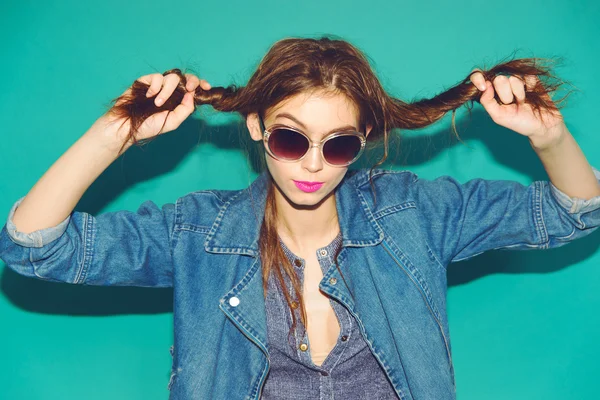 Emotionale hübsche junge Hipster-Mädchen machen lustiges Gesicht auf blauem Hintergrund — Stockfoto
