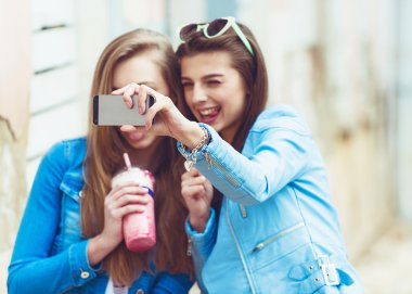 Hippi kız arkadaşlarım an modern smartphone ile eternalizing bir selfie - dostluk ve yeni trendler ve teknoloji ile eğlenceli kavramı - kentsel şehir bağlamda alarak