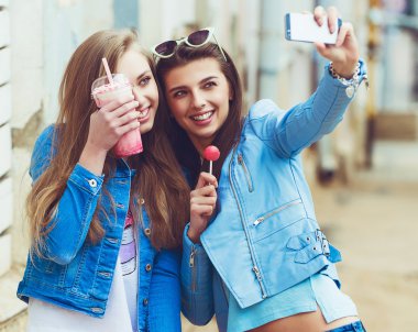 Hippi kız arkadaşlarım an modern smartphone ile eternalizing bir selfie - dostluk ve yeni trendler ve teknoloji ile eğlenceli kavramı - kentsel şehir bağlamda alarak
