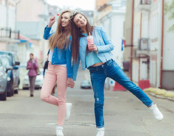 Hermosas chicas jóvenes novias hipster posando con un asiento de monopatín en el patín, estilo de vida de moda callejera en gafas de sol — Foto de Stock