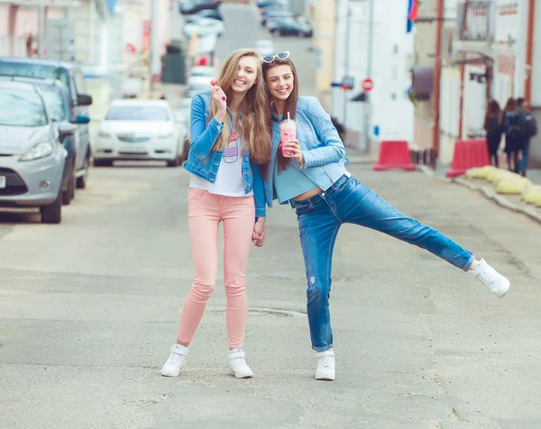 Beautiful young girls hipster girlfriends posing with a skateboard seat on skate, street fashion lifestyle in sunglasses — Stock Photo, Image