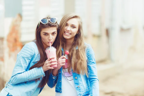 Beautiful young girls hipster girlfriends posing with a skateboard seat on skate, street fashion lifestyle in sunglasses — Stock Photo, Image