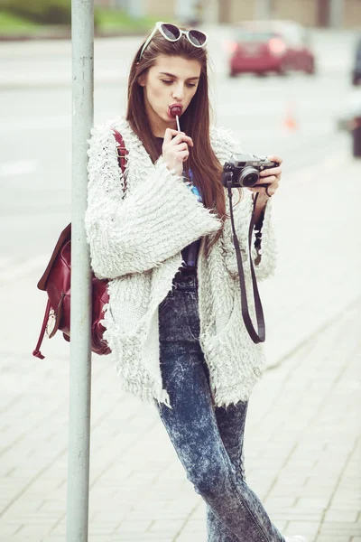 Fashion women tourist keep digital compact camera and look photo on screen. Hipster  style sunglasses and coat. Outdoor portrait Stock Photo by ©Rattleray  71906951