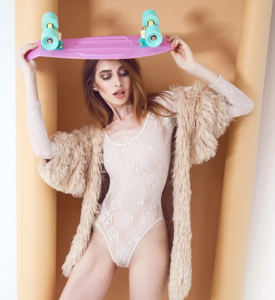 Fashion model seksi dalam mantel bulu dan lingerie mempromosikan longboard di studio — Stok Foto