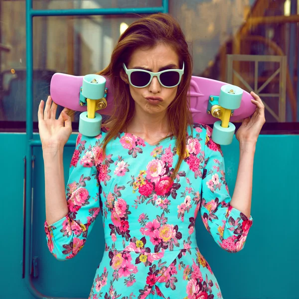 Beautiful and fashion young woman posing with a skateboard on city street — Stock Photo, Image