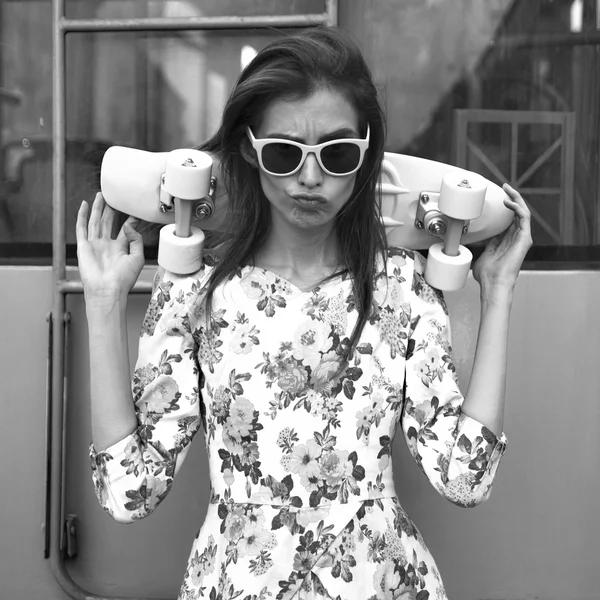 Beautiful and fashion young woman posing with a skateboard on city street — Stock Photo, Image