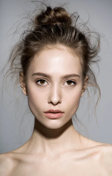 Vrouw model met verse dagelijkse make-up en grappige golvende kapsel. Mode glanzende markeerstift op huid, sexy glans lippen make-up en natuurlijke wenkbrauwen. grijze achtergrond — Stockfoto