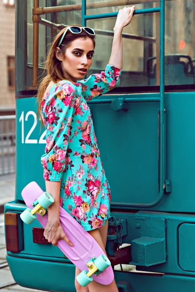 Mujer joven hermosa y de moda posando con un monopatín en la calle de la ciudad — Foto de Stock