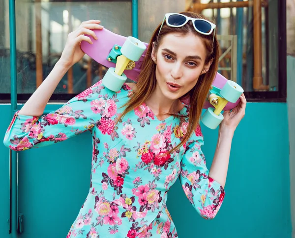 Mujer joven hermosa y de moda posando con un monopatín en la calle de la ciudad — Foto de Stock