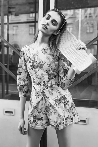 Mooi en mode jonge vrouw poseren met een skateboard op ci — Stockfoto