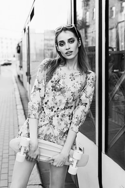 Mooi en mode jonge vrouw poseren met een skateboard op ci — Stockfoto