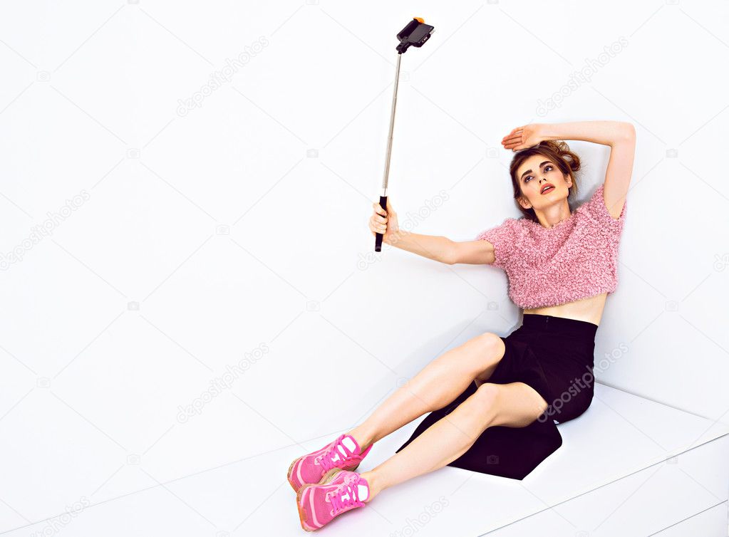 Young fashion model woman taking a selfie with phone on monopod