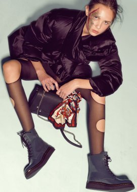 Tasarım kıyafetler ve mavi çanta moda model açık renk arka plan üzerinde poz verdi.