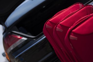 Bir araba bagajı için hazır önünde üç kırmızı bavul seyahat