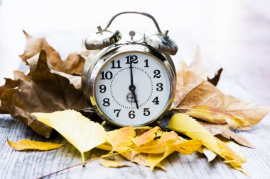 Sonbahar yaprakları ile ahşap bir Masa Retro saat