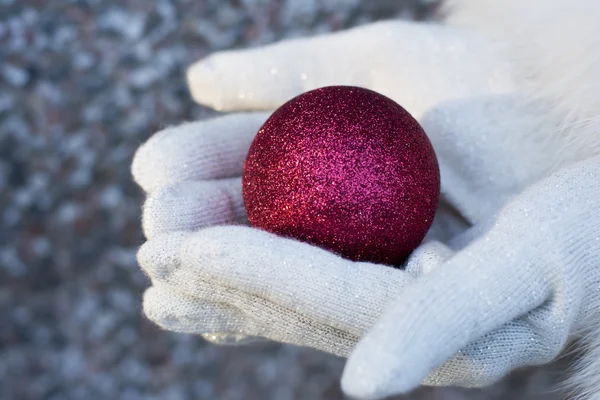 Voman donnant boule d'arbre de Noël portant des gants rouges — Photo