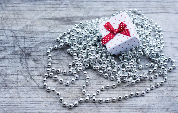 White gift box with red dots upon silver pearls — Stock Photo, Image