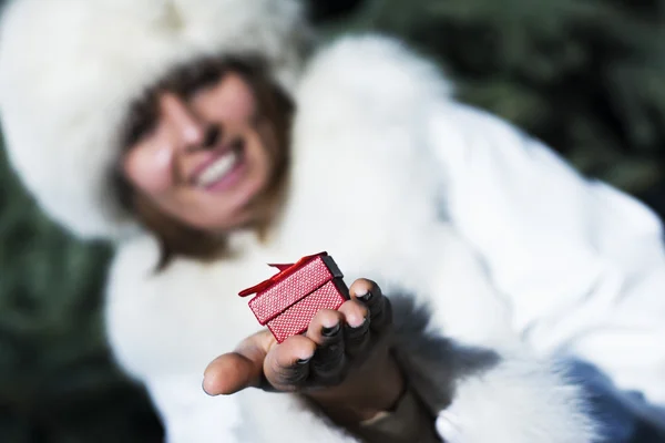 Leende kvinna ger en röd presentförpackning för semester — Stockfoto