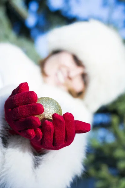 Donna sorridente dando palla albero di Natale indossando guanti rossi — Foto Stock