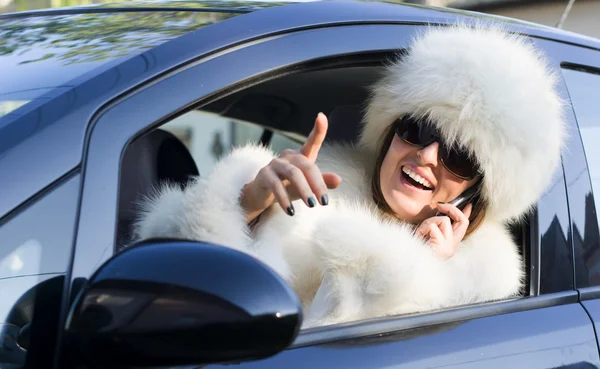 Vrouw in witte vacht op de telefoon smiling — Stockfoto