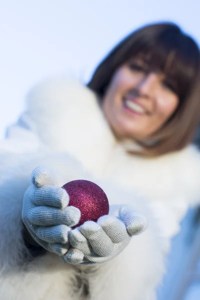 Voman ger julgran bollen bär röda handskar — Stockfoto