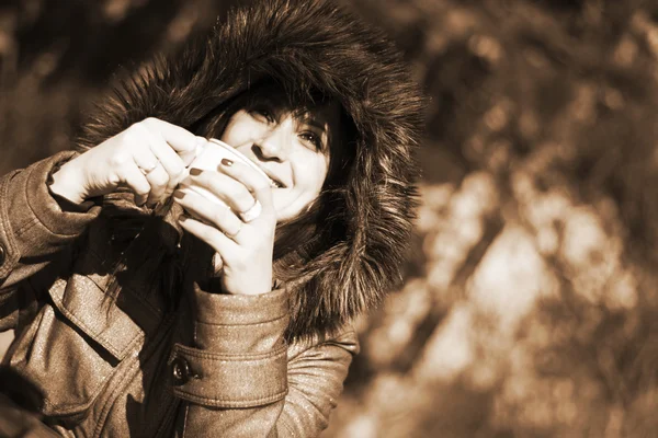 Donna in giacca con cappuccio bere caffè caldo all'aperto — Foto Stock