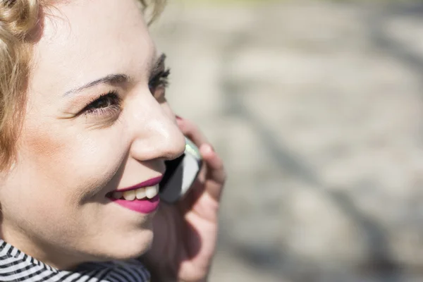 Fiatal göndör szőke nő beszél a telefonon, a szabadban — Stock Fotó