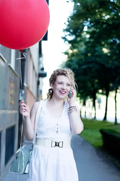 Kudrnatá blondýnka s velkým červeným ballon na telefonu — Stock fotografie