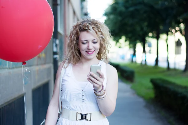 Kudrnatá blondýnka s velkým červeným ballon na telefonu — Stock fotografie