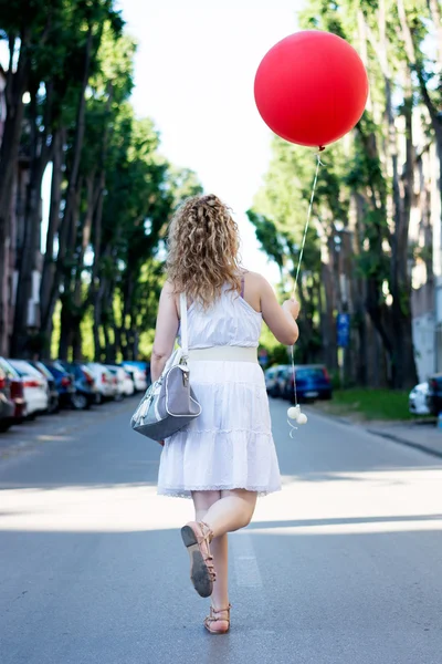 Fille blonde bouclée avec grand ballon rouge — Photo