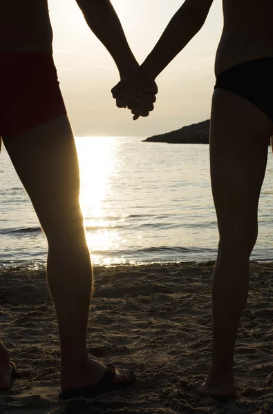 Casal em uma praia de mãos dadas ao pôr do sol — Fotografia de Stock