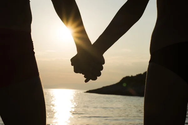 Coppia su una spiaggia che si tiene per mano al tramonto — Foto Stock