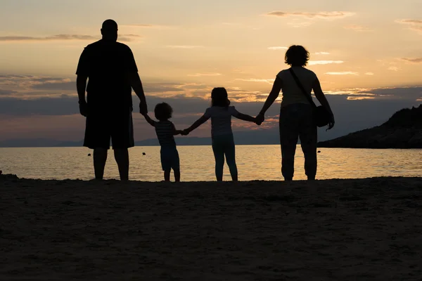 Famiglia su una spiaggia che si tiene per mano al tramonto Foto Stock Royalty Free