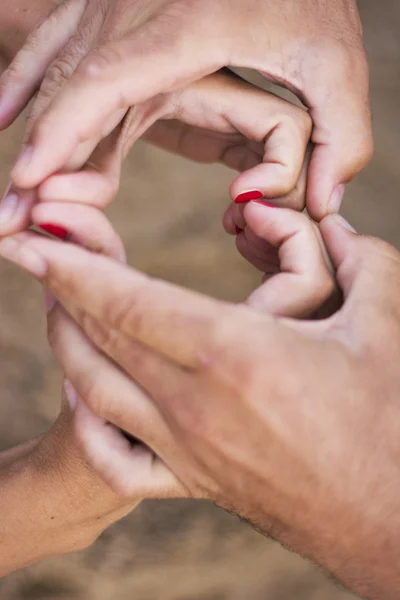 Pareja haciendo forma de corazón de manos — Foto de Stock