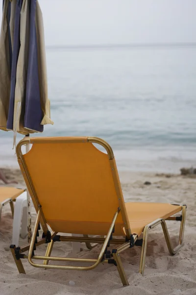 Sillas de cubierta y sombrilla en una playa —  Fotos de Stock