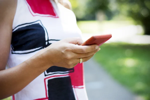 Mujer morena bonita usando teléfono inteligente en el parque —  Fotos de Stock