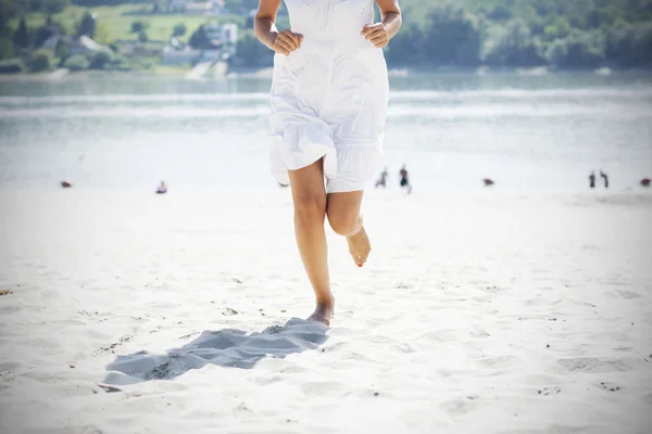 Kvinnan i vit körs på stranden — Stockfoto