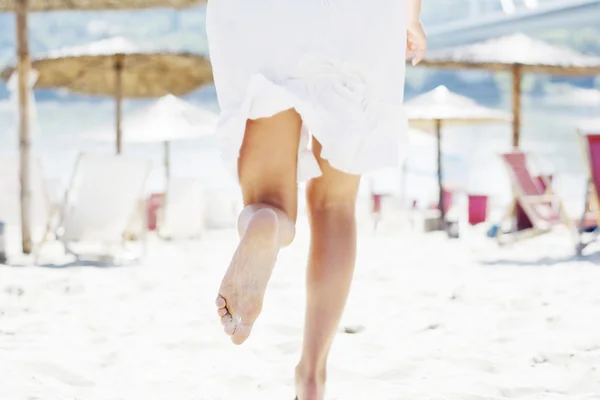 Mujer en blanco corriendo en la playa — Foto de Stock
