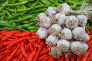 Kırmızı biberli arka planda bir yığın sarımsak.