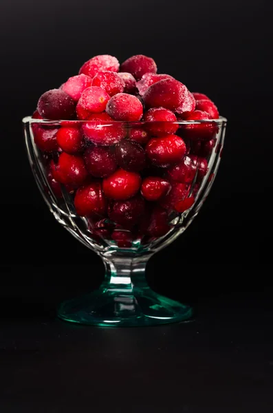 Cranberries congelados em uma tigela de vidro no fundo preto — Fotografia de Stock