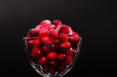 siyah arka plan üzerine bir cam kabın içinde donmuş kızılcık