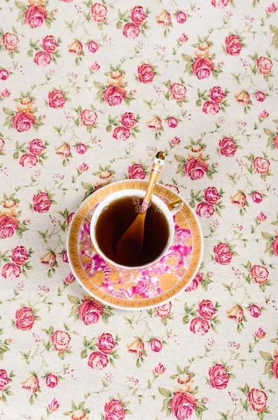 Antique tea cup full of tea on floral background — Stock Photo, Image