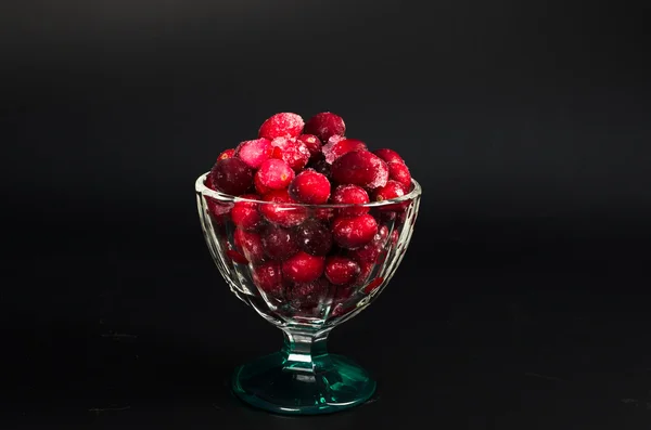 Frysta tranbär i en glasskål på svart bakgrund — Stockfoto
