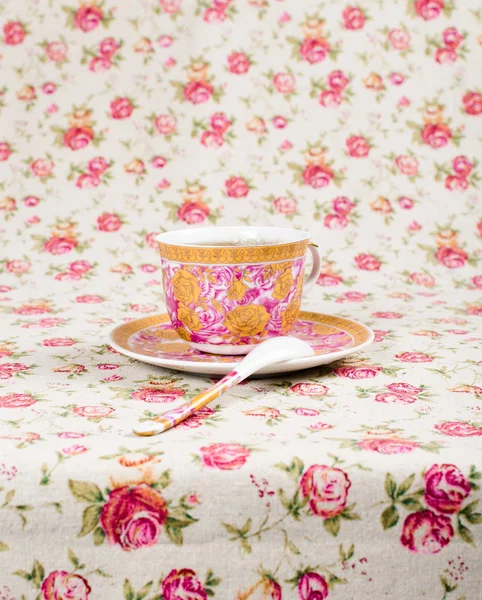 Tazza di tè antico pieno di tè su sfondo floreale — Foto Stock