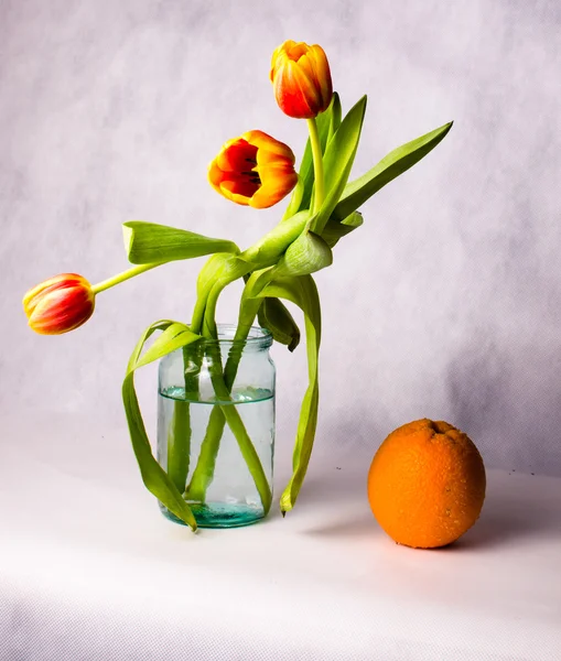 Bouquet de tulipes dans un bocal en verre et orange en gouttelettes d'eau sur — Photo