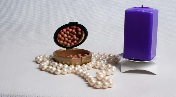 Pearl beads, a box of rouge and purple square candle in a candle — Stock Photo, Image
