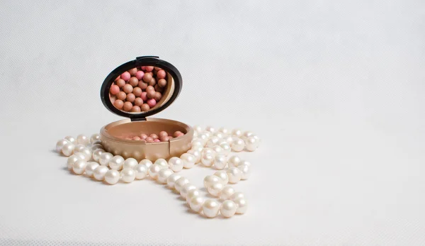 Perlen und eine Schachtel Rouge auf hellem Hintergrund — Stockfoto
