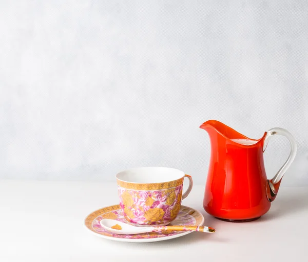 Antique cup and saucer and milk in a glass jar orange — Stock Photo, Image