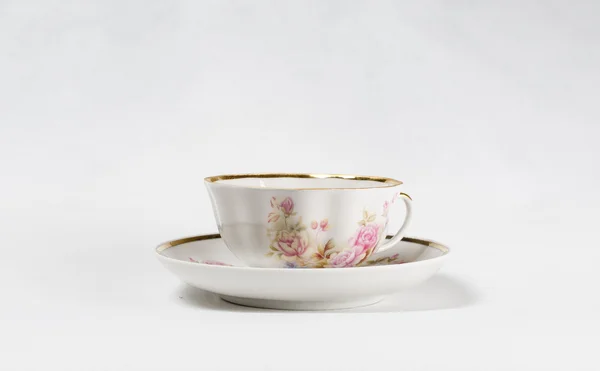 Cangkir teh porselen antik dengan lukisan bunga di latar belakang putih — Stok Foto