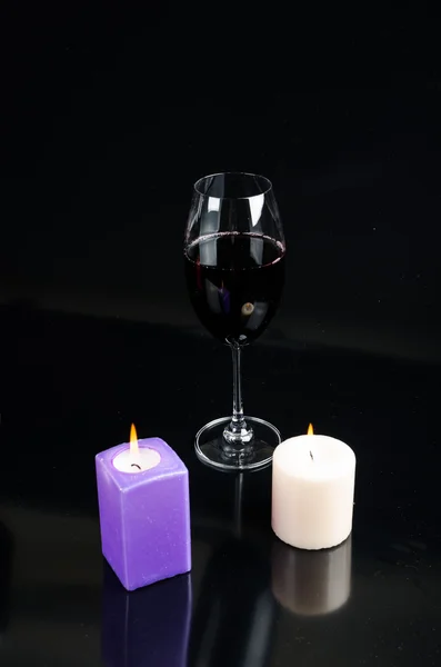 Glass of wine and a candle on a black background — Stock Photo, Image